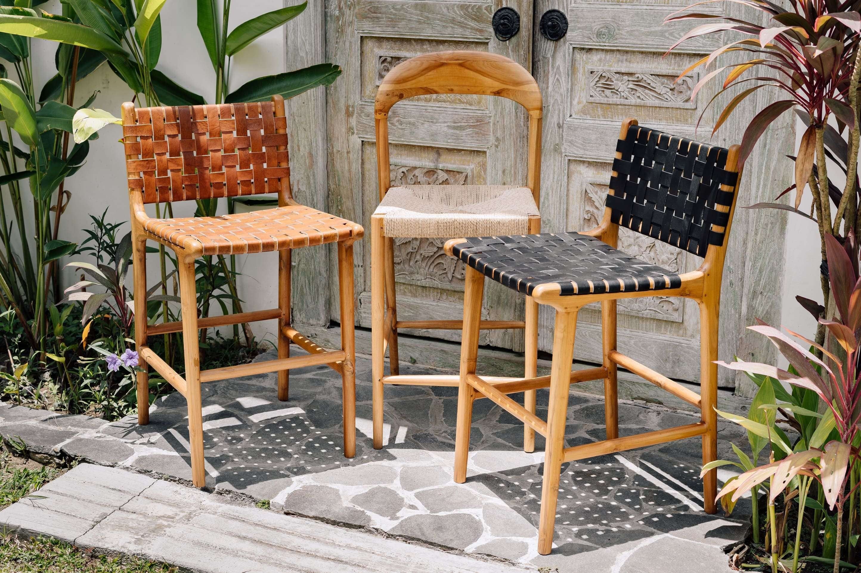 Kayu Living Cemagi teak counter stool with woven tan leather seat and backrest. Modern design for indoor/outdoor use.