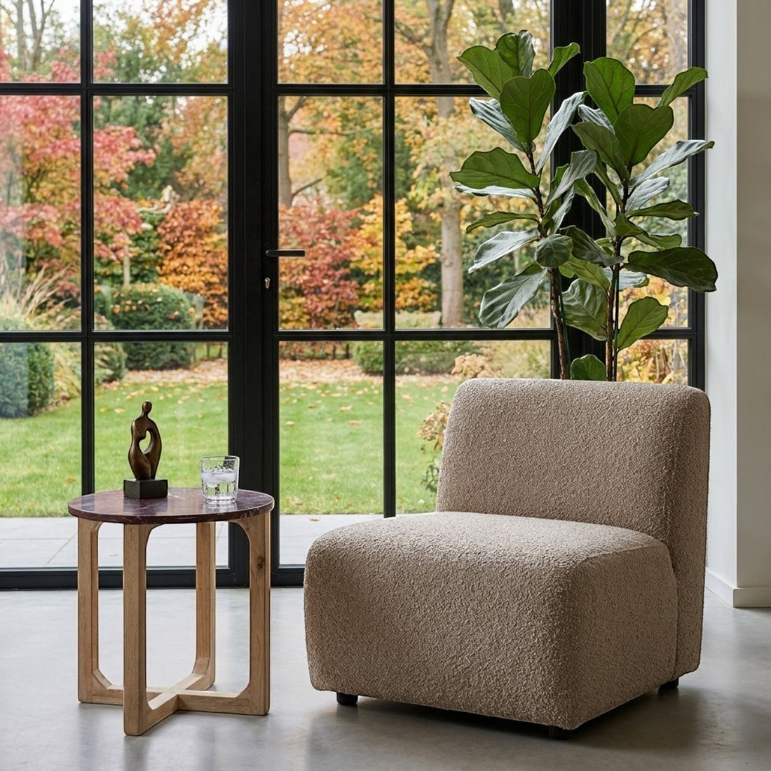 Kayu Living burgundy marble side table with white veins and mango wood cross-leg base next to a textured armchair.