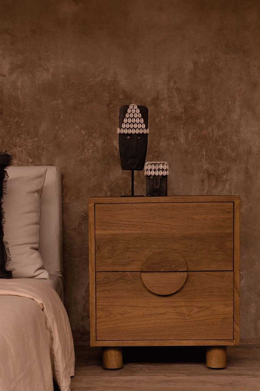 Kayu Living Eclipse nightstand in solid teak with two drawers and a circular handle in a warm, modern bedroom.