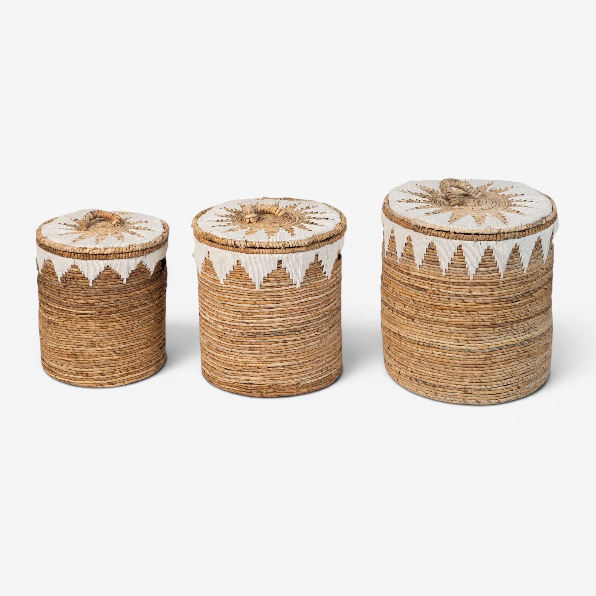 Kayu Living set of 3 natural banana cord storage baskets with white embroidered lids and decorative trim.