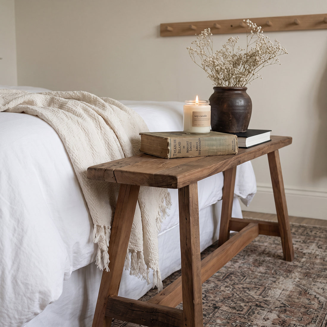 Kayu Living Farmwood 115cm reclaimed wood bench styled as a bedside table with a candle and books in a bedroom