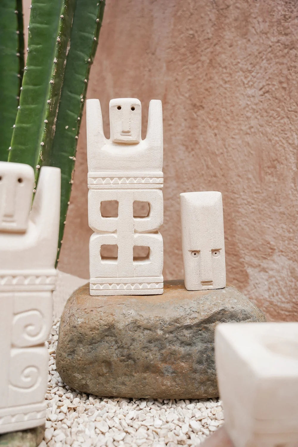 Kayu Living hand-carved stone guardian figurine with natural finish, displayed on a rock with a cactus background.