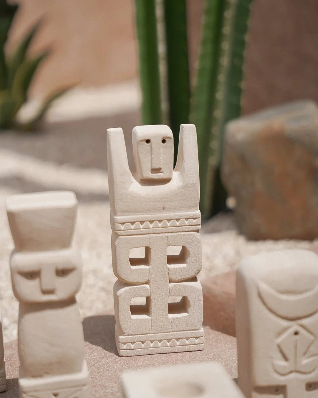 Kayu Living hand-carved stone guardian figurine with natural finish and geometric carvings in a desert setting