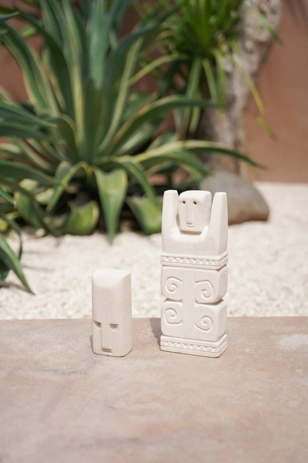 Kayu Living handcrafted Balinese natural stone guardian figurines with carved spiral details on a stone surface.