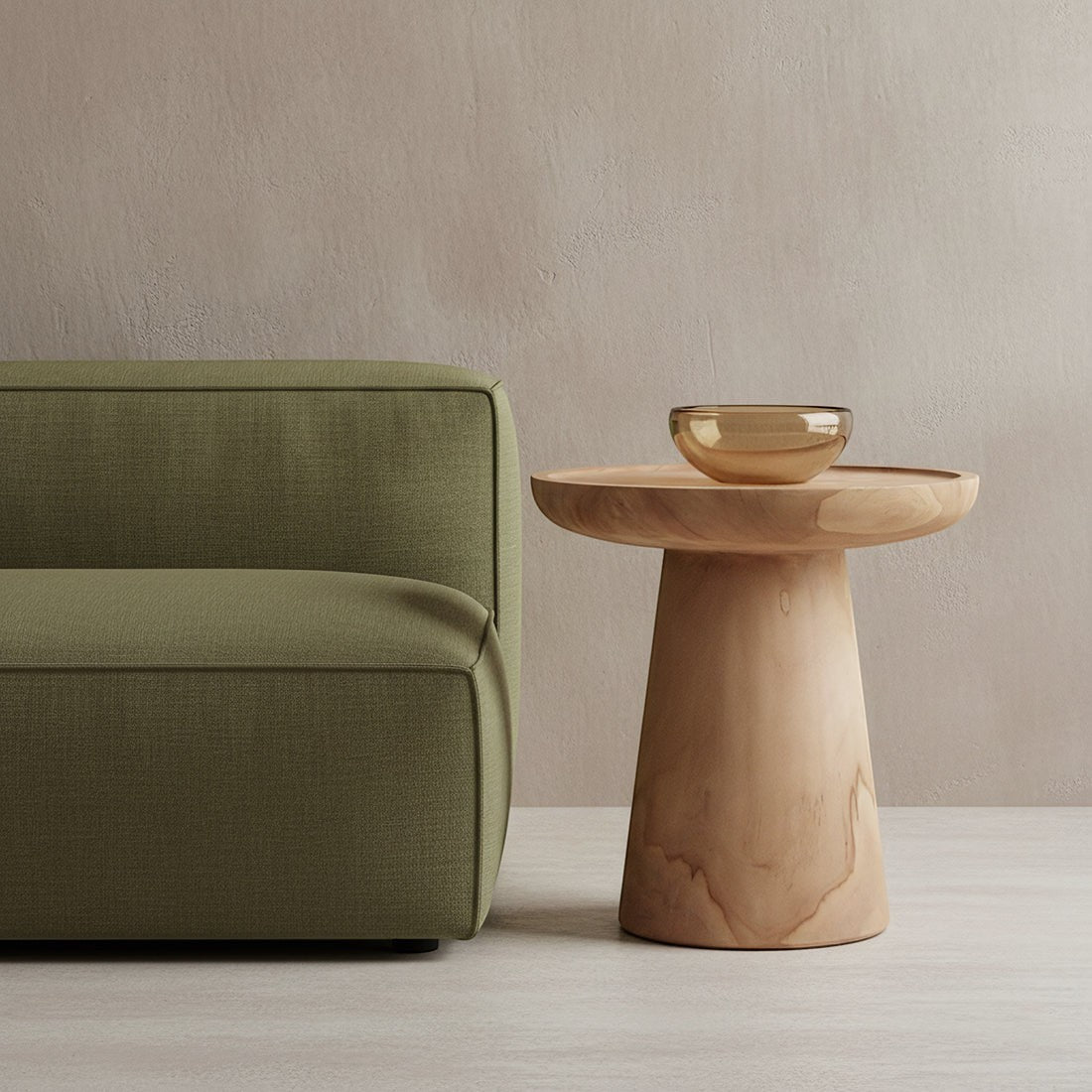Kayu Living Nero Ray side table in natural teak wood with a pedestal base next to a modern olive green sofa