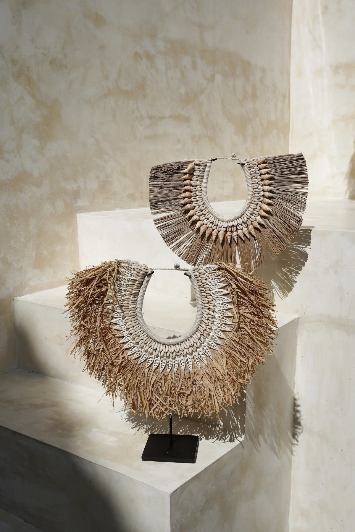 Kayu Living handcrafted seagrass and seashell wall art on a black metal stand, featuring organic coastal textures.
