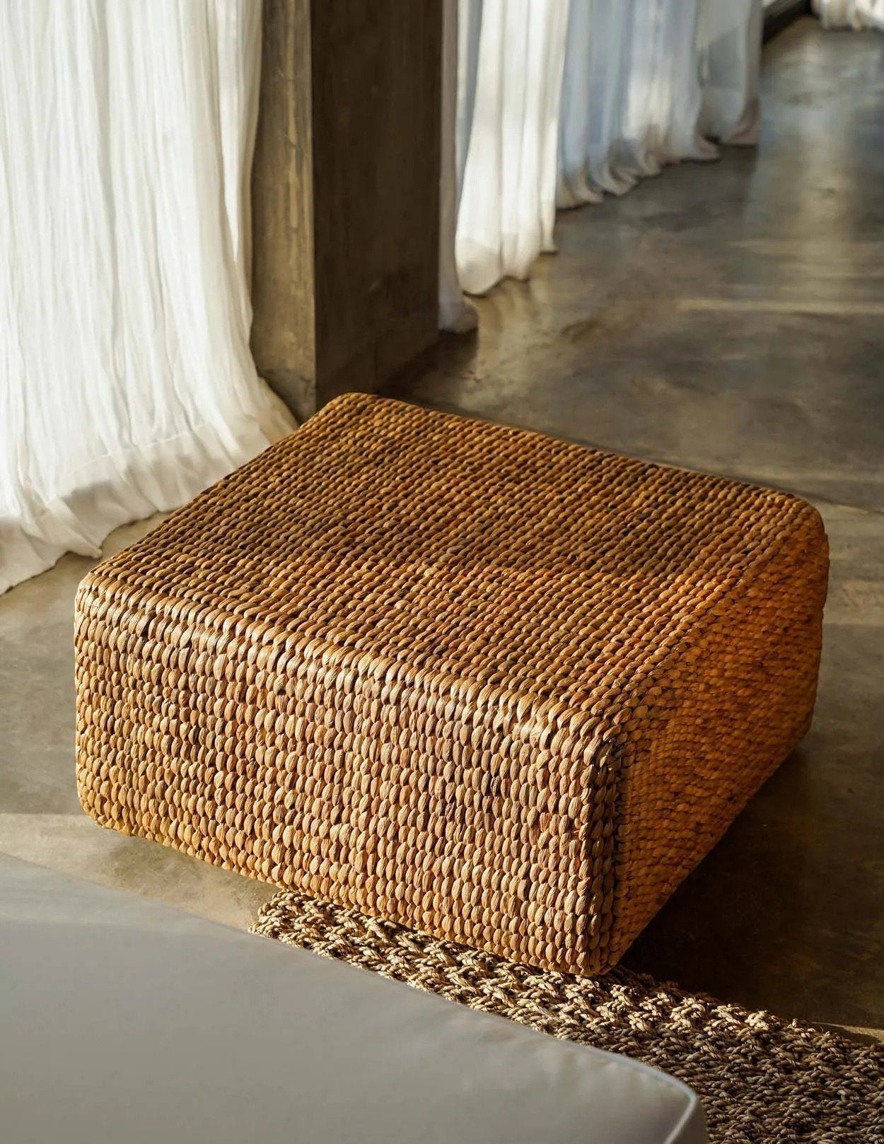 Kayu Living square water-hyacinth pouf in natural tan, featuring a durable woven texture for indoor or outdoor use.