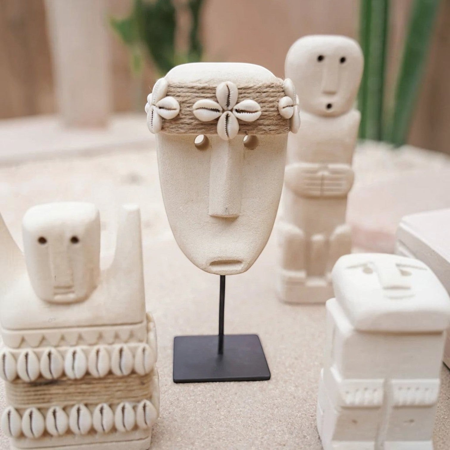 Kayu Living handcrafted stone mask figurine on a black metal stand, decorated with jute rope and cowrie shells.