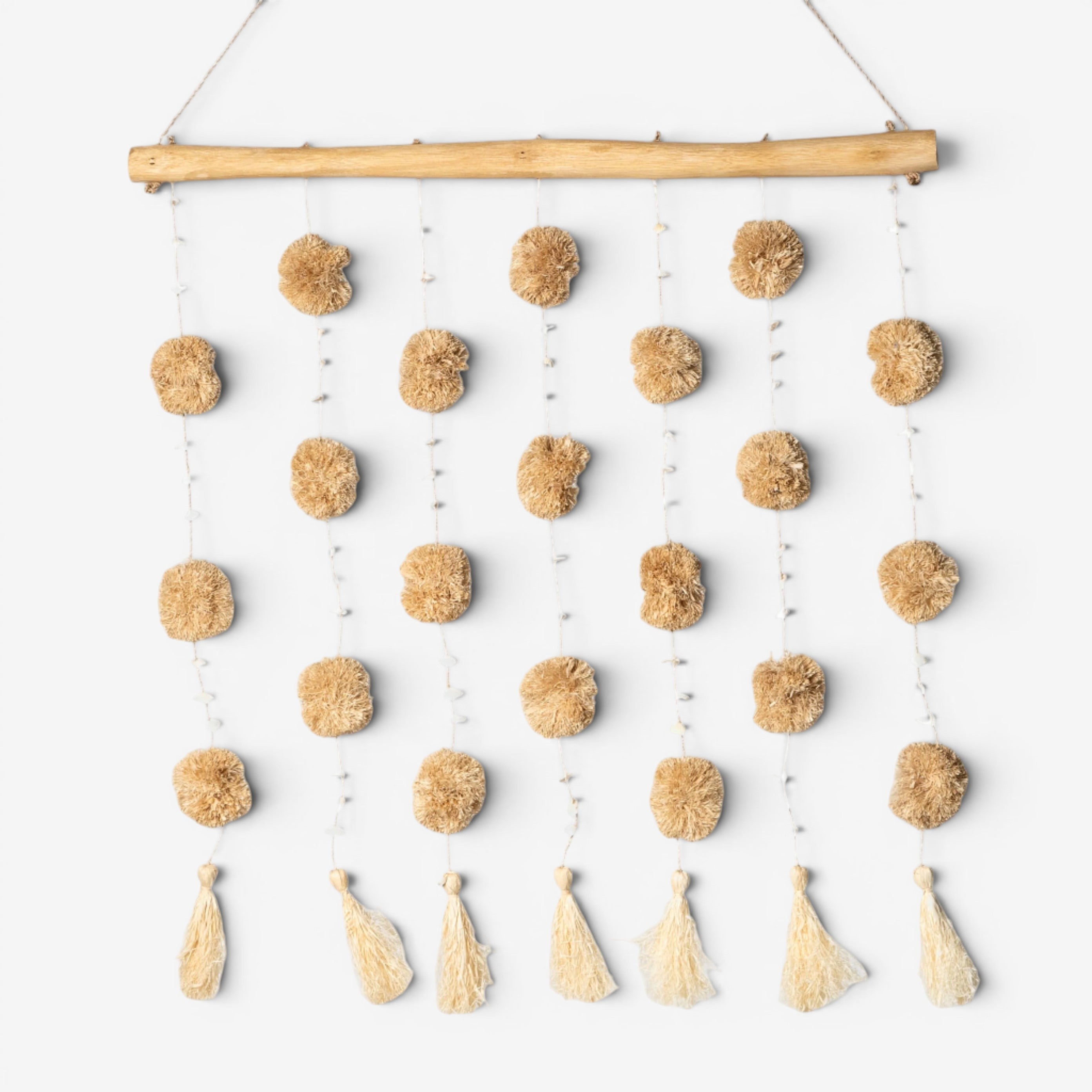 Kayu Living natural tan pom pom wall hanging with tassels and wooden dowel.