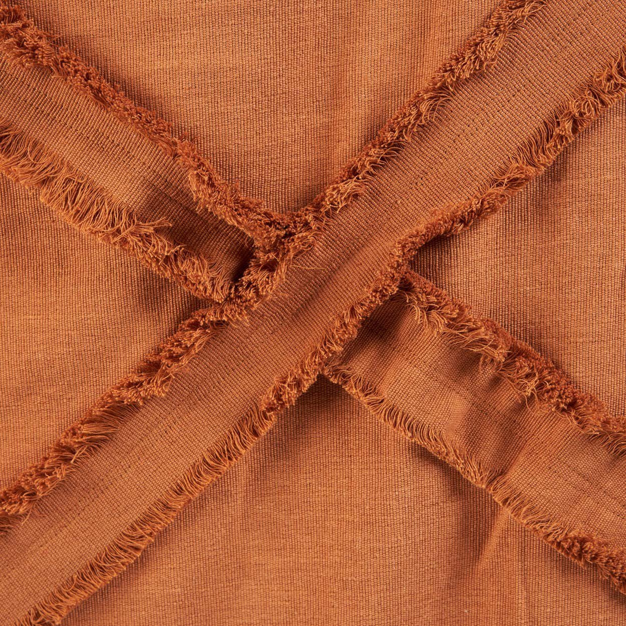 Kayu Living terracotta cotton throw blanket with a textured plaid design and frayed fringe edges.