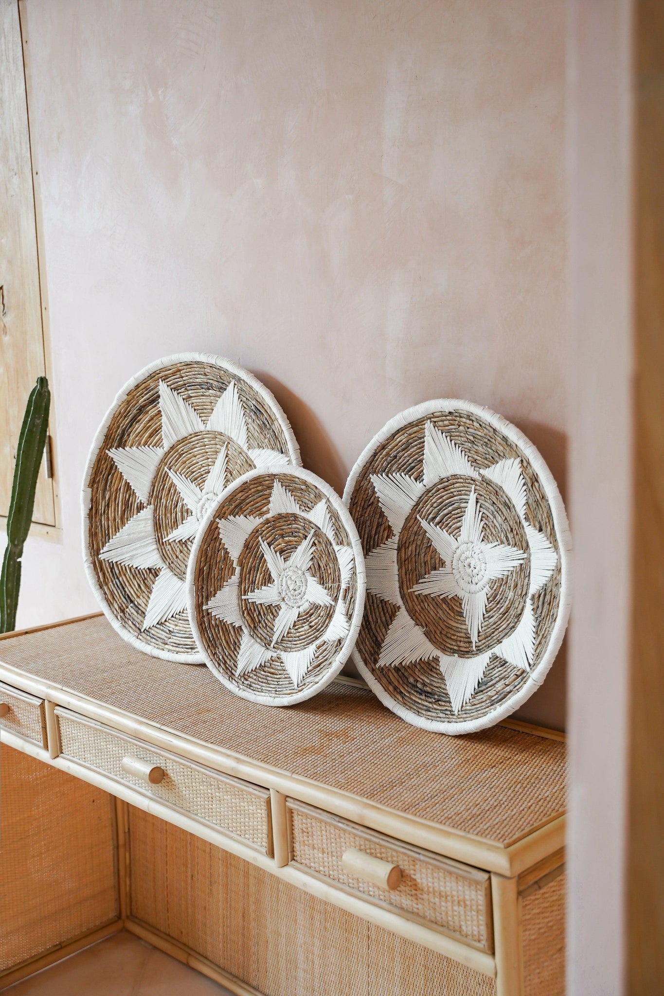 Kayu Living Uluwatu brown and white handmade banana leaf and cotton wall baskets with star patterns on rattan console.